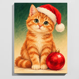 Christmas cat paint by numbers kit: finished painting of a ginger kitten in a Santa hat sitting beside a red Christmas bauble