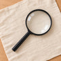 Black handheld magnifying glass on linen