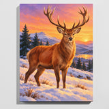 Stag in the snow paint by numbers kit: finished painting of a red deer stag standing in snow at a winter sunset with pine trees and hills